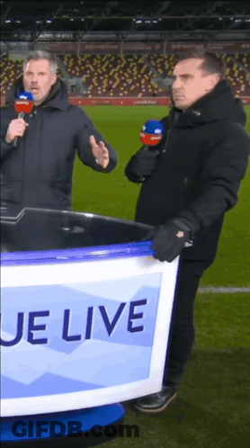 Two Men Standing In Front Of A Sign That Says ' Je Live ' GIF