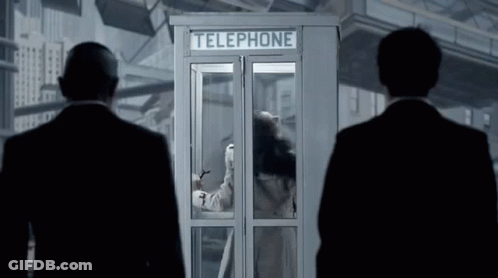 Two Men Standing In Front Of A Telephone Booth With A Woman Inside GIF