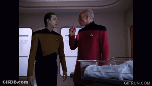 Two Men Standing In Front Of Baby In Crib GIF