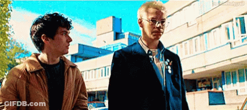 Two Men Standing In Front Of Building GIF