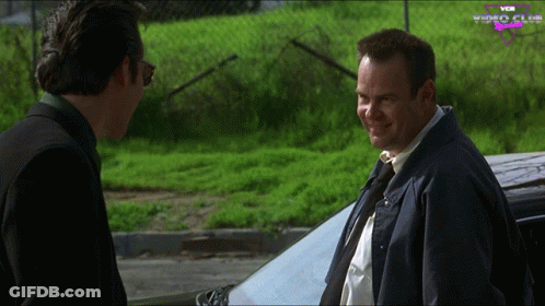 Two Men Standing In Front Of Car With Vox Video Club GIF