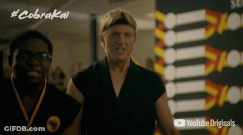 Two Men Standing In Front Of Cobra Kai Sign GIF