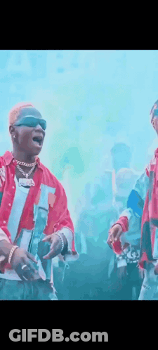 Two Men Standing In Front Of Crowd One Wearing Sunglasses GIF