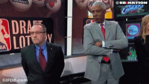 Two Men Standing In Front Of Draft Lottery Sign GIF