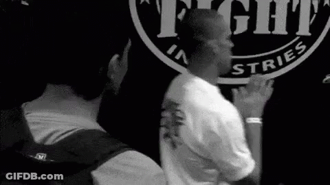 Two Men Standing In Front Of Fight Industries Sign GIF