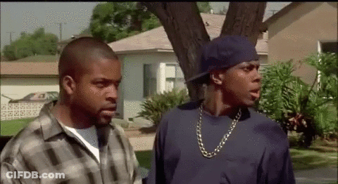 Two Men Standing In Front Of House One In Blue Hat GIF