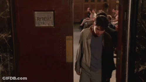 Two Men Standing In Front Of Room Sign GIF