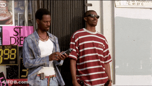 Two Men Standing In Front Of St. Dxe Sign GIF