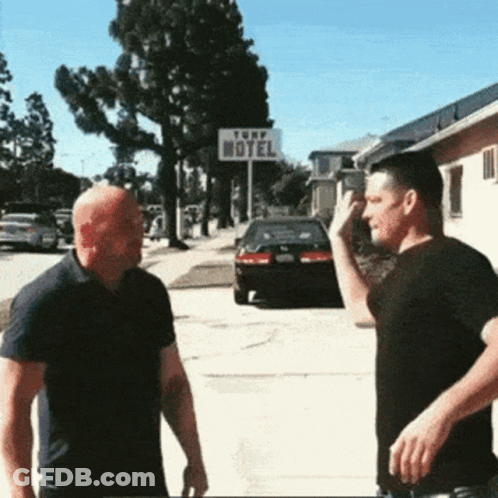 Two Men Standing In Front Of Turf Motel Sign GIF