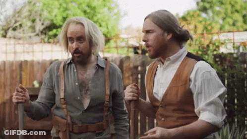 Two Men Standing In Front Of Wooden Fence Talking GIF