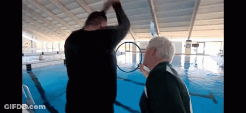 Two Men Standing In Pool Looking At Ring GIF