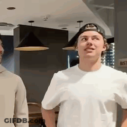 Two Men Standing In Room One Wearing Cap GIF