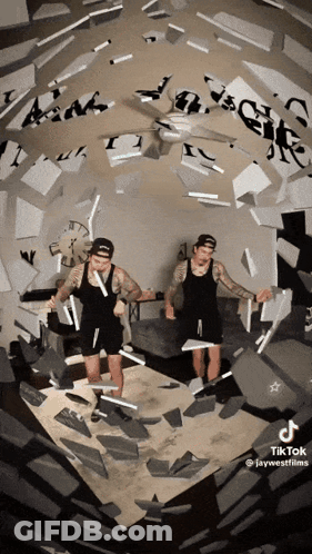 Two Men Standing In Room With Ceiling Fan And Clock GIF