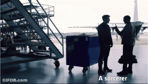 Two Men Standing Next To A Blue Box That Says ' A Sorcerer ' On The Bottom GIF