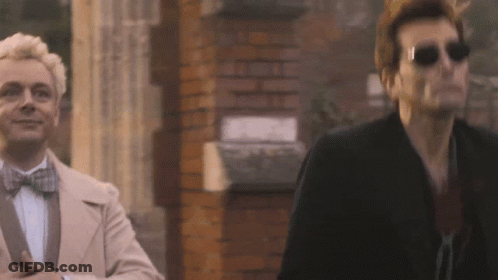 Two Men Standing Next To Brick Wall GIF