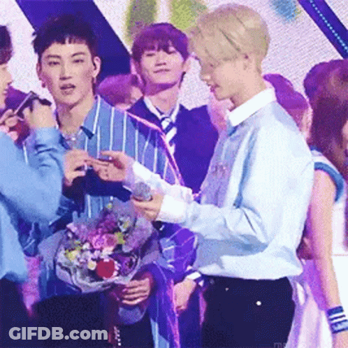 Two Men Standing Next To Each Other Holding Microphone On Stage GIF
