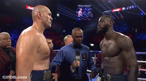 Two Men Standing Next To Each Other In A Boxing Ring With Coca Cola Advertisements On The Screen GIF