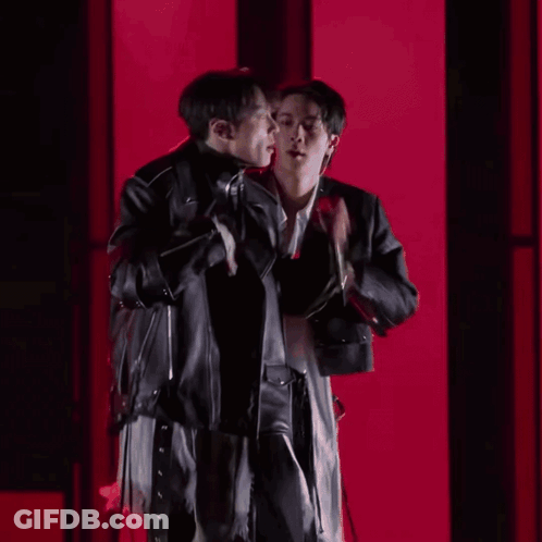 Two Men Standing Next To Each Other In A Dark Room GIF