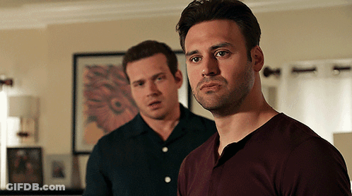 Two Men Standing Next To Each Other In A Living Room Looking At The Camera GIF