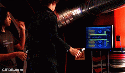 Two Men Standing Next To Each Other In A Room With A Blue Pipe In The Background GIF