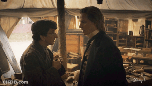 Two Men Standing Next To Each Other In A Room With A Disney+ Logo On The Bottom GIF