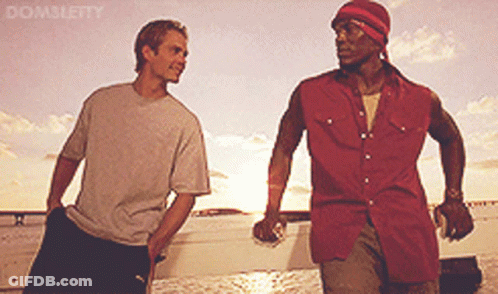 Two Men Standing Next To Each Other In Front Of A Body Of Water With Domsleity Written On The Bottom GIF