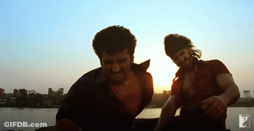 Two Men Standing Next To Each Other In Front Of A Sunset GIF