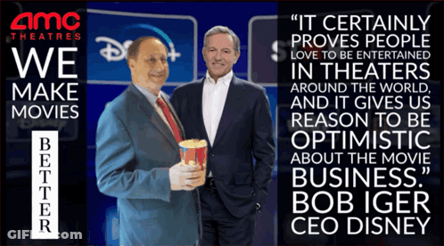 Two Men Standing Next To Each Other In Front Of An Amc Theatres Sign GIF