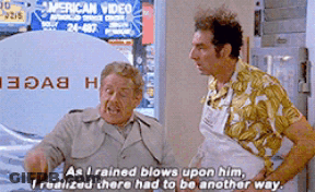 Two Men Standing Next To Each Other In Front Of An American Video Sign GIF