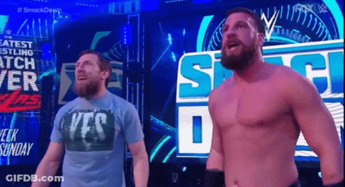 Two Men Standing Next To Each Other In Front Of Smackdown Sign GIF