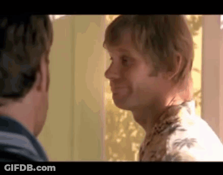 Two Men Standing Next To Each Other Looking At Each Other One In Hawaiian Shirt GIF