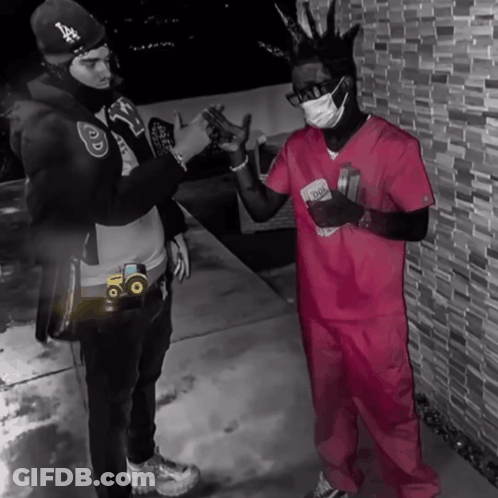 Two Men Standing Next To Each Other One Wearing A Pink Scrub Top And The Other Wearing A Mask GIF