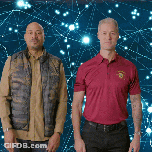 Two Men Standing Next To Each Other One Wearing Texas Shirt GIF