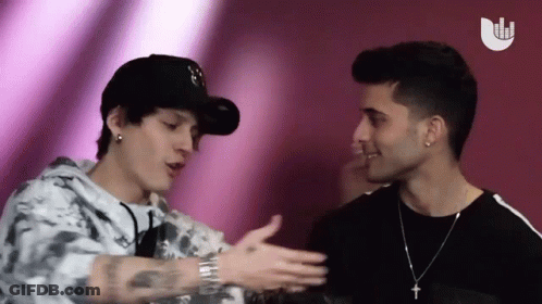 Two Men Standing Next To Each Other With Cross Necklace GIF