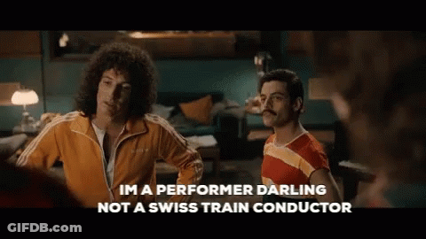 Two Men Standing Next To Each Other With The Words Im A Performer Darling Not A Swiss Train Conductor Written Below Them GIF