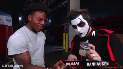 Two Men Standing Next To Raw Danhausen Sign GIF