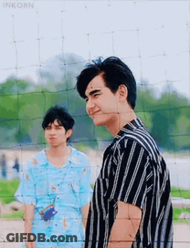 Two Men Standing Next To Volleyball Net GIF