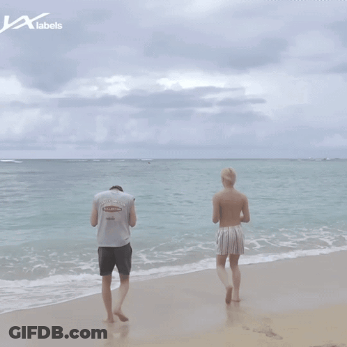 Two Men Standing On A Beach With A Label That Says Labels On It GIF