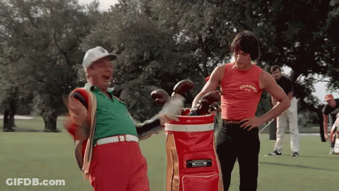 Two Men Standing On A Golf Course With One Wearing A Shirt That Says ' Simpson ' GIF