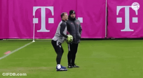 Two Men Standing On Soccer Field Holding Ball GIF
