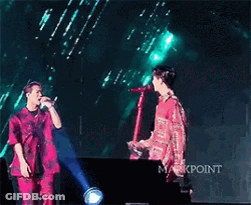 Two Men Standing On Stage Holding Microphone GIF