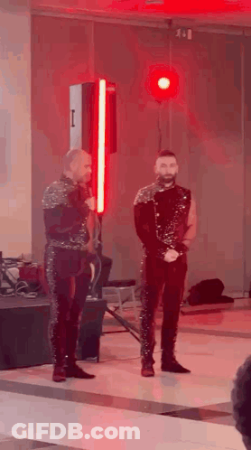 Two Men Standing On Stage With Red Light GIF