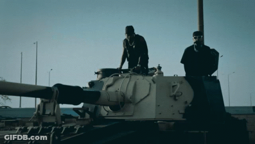 Two Men Standing On Tank Number 7 GIF