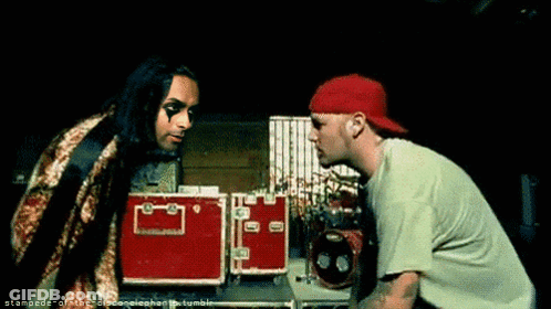Two Men Standing One In Green Shirt And Red Hat GIF