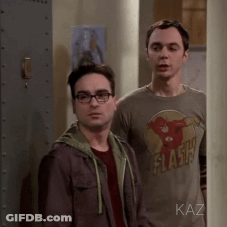 Two Men Standing, One Wearing Flash Shirt GIF
