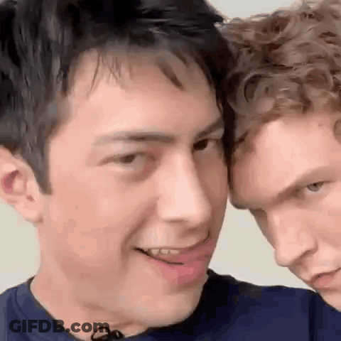 Two Men Standing Together One Smiling GIF