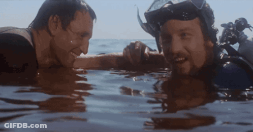 Two Men Swimming In Ocean One Wearing Goggles GIF