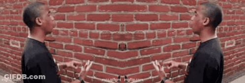 Two Men Talking Beside Red Brick Wall GIF