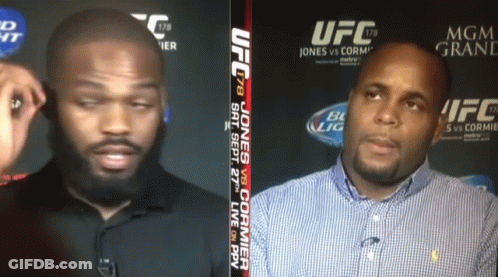 Two Men Talking In Front Of UFC Sign GIF
