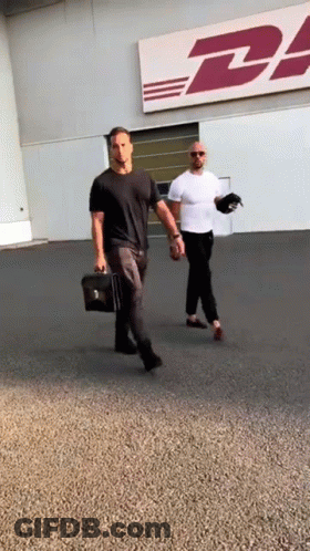Two Men Walk In Front Of DHL Sign GIF